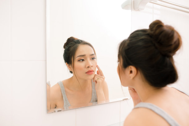 在家中浴室照镜子的微笑年轻女人素材图片