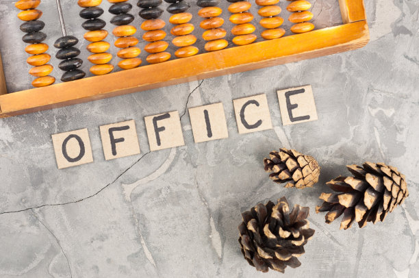 Word OFFICE在破旧的木质算盘旁的硬纸板上放着手写的字母，灰色裂缝混凝土上有三个圆锥体图片下载