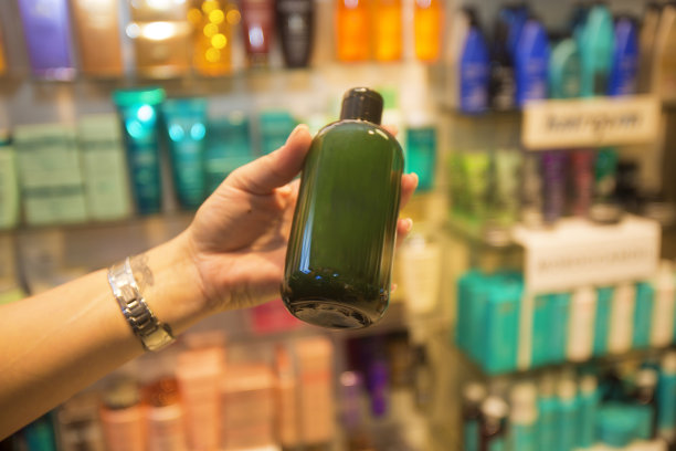 一个女人拿着一个美容产品在一个摆满产品的药店的货架前图片下载