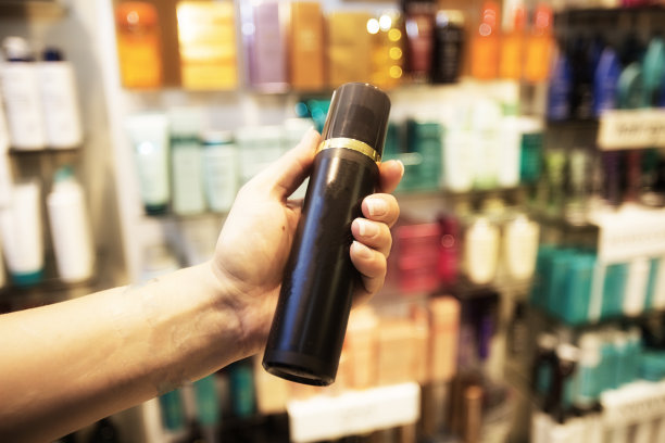 一个女人拿着一个美容产品在一个摆满产品的药店的货架前图片下载