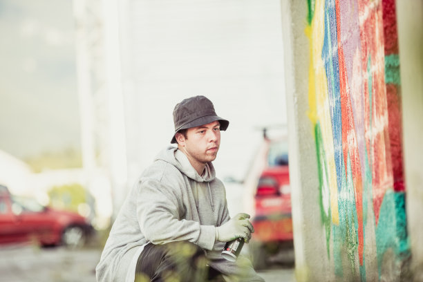 年轻的涂鸦艺术家看着他的不完整的涂鸦图片下载