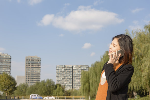 年轻的亚洲孕妇在公园桥上打电话图片下载