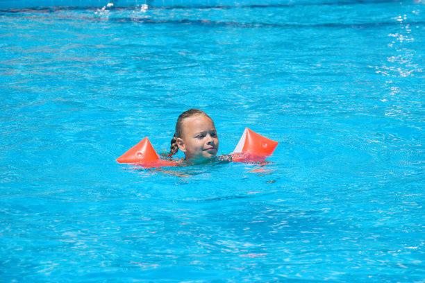 可爱的小女孩在外面的游泳池里学习游泳图片下载