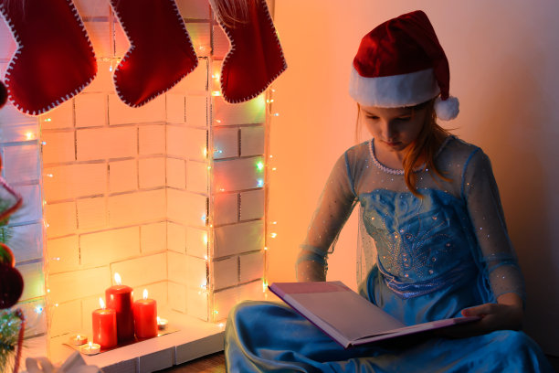 女孩穿着衣服和书靠近壁炉图片下载