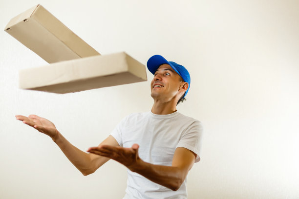 年轻的送货员，手里拿着一堆掉下来的箱子。孤立在白色图片下载