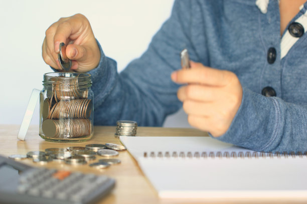 存钱理财理念，女性手把钱放入玻璃瓶，复古色调图片下载