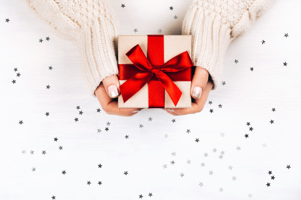 女性手握礼品，红色蝴蝶结图片下载