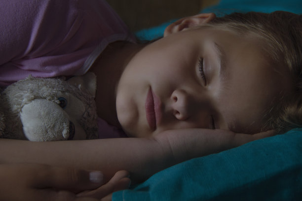 金发小孩儿在床上玩玩具。素材图片