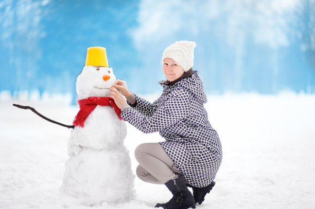 中年妇女在雪地公园堆雪人肖像素材图片