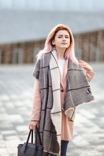 美丽的时尚女孩走在街上的包和微笑的相机图片下载