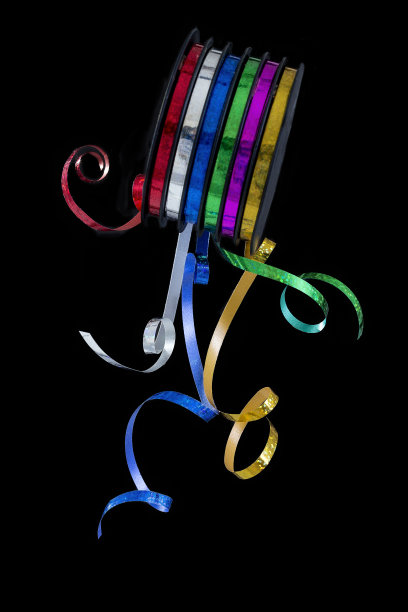 彩色卷卷曲的丝带在一个黑色的背景特写图片下载