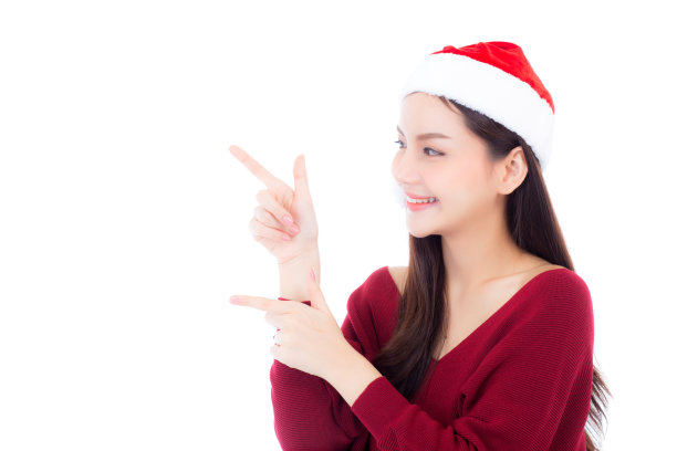 美丽的亚洲年轻女子肖像在圣诞老人的帽子微笑和快乐的东西，女孩模特孤立在白色的背景，圣诞节和假日的概念。图片下载