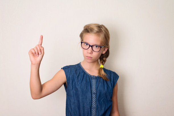 戴眼镜的女孩竖着手指。消极的人类情绪，面部表情或肢体语言。听我的。图片下载