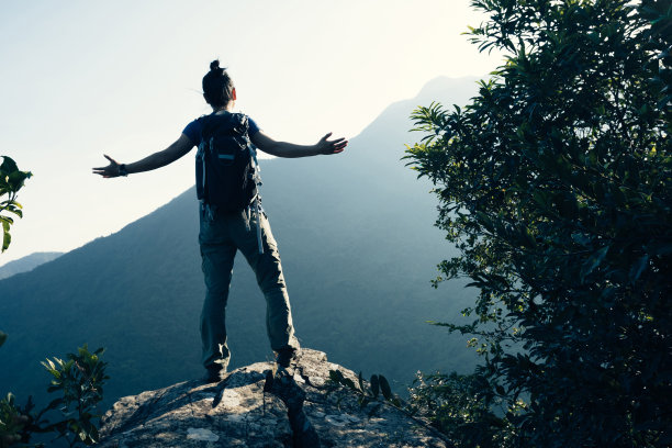 成功的女背包客在悬崖边上跳图片下载