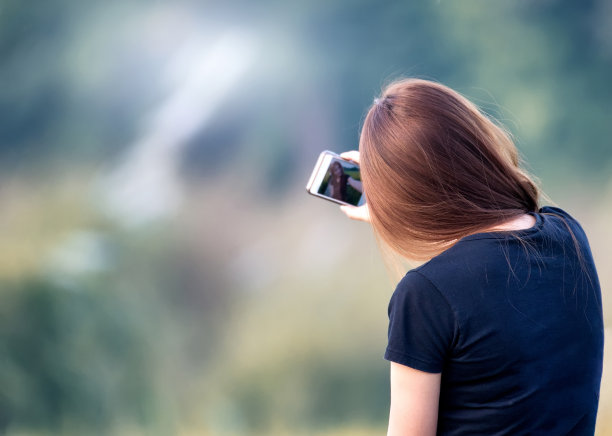 年轻女子正在用智能手机自拍。图片下载
