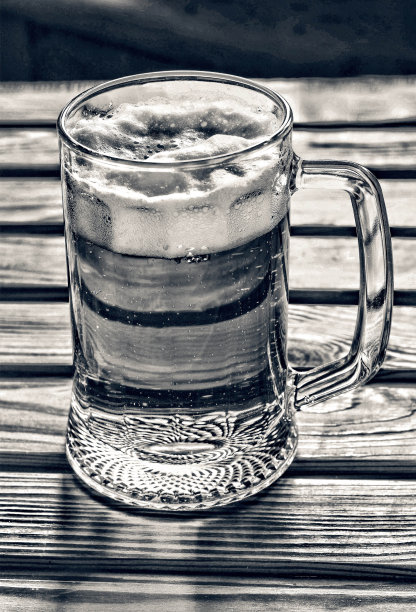 酒吧的木桌上放着一大杯淡啤酒泡沫丸图片下载