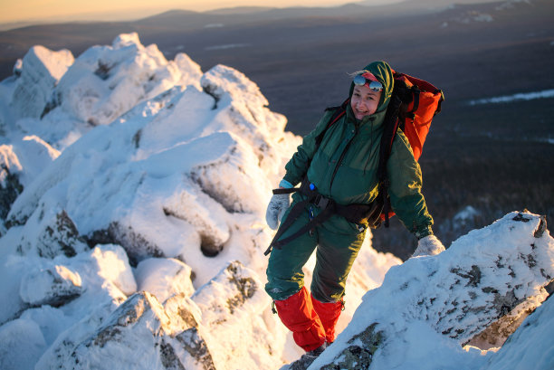 快乐的女人徒步旅行者背着背包站在山顶，微笑在寒冷的冬日。女性英雄和积极的生活理念。图片下载
