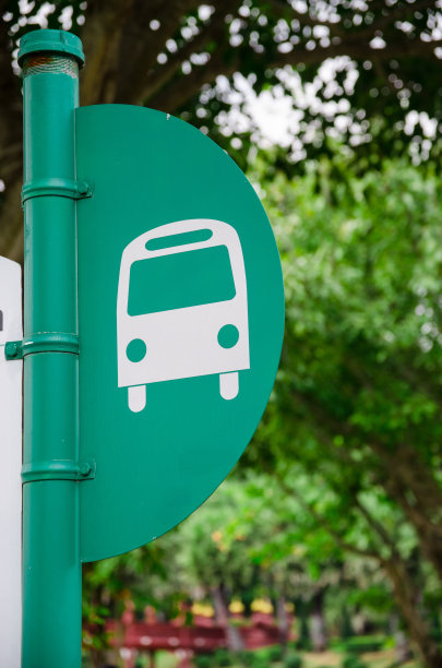 在绿树背景下的公交车站杆子图片下载