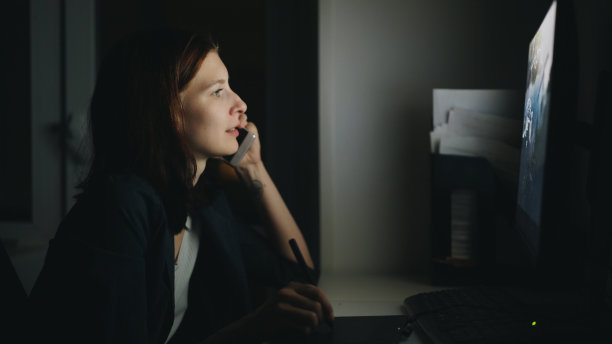 专注的女性设计师打电话，晚上在办公室用电脑和图形平板电脑完成工作图片下载