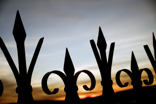 复古风格的铸铁栅栏，日落天空的背景。图片下载