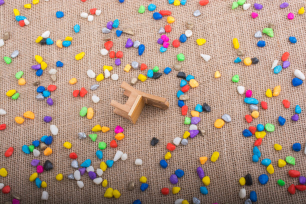 帆布背景上铺着五颜六色的鹅卵石，中间是一把小椅子图片下载