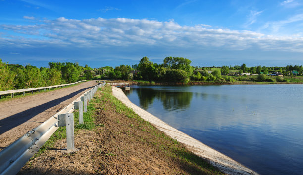 经过大坝的乡村公路。阳光明媚的春天，乡村景观与河流。图片下载