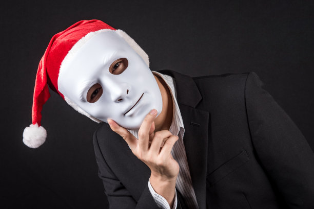 年轻的亚洲商人戴着白色面具和圣诞老人帽图片下载
