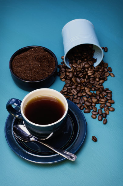 蓝色的咖啡杯和溢出的咖啡豆图片下载