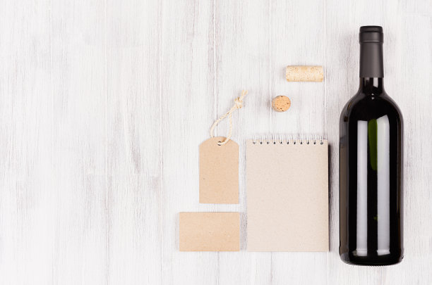 模仿的空白米色卡夫包装，文具，商品与酒瓶红酒在软白色木材背景，复制空间。图片下载