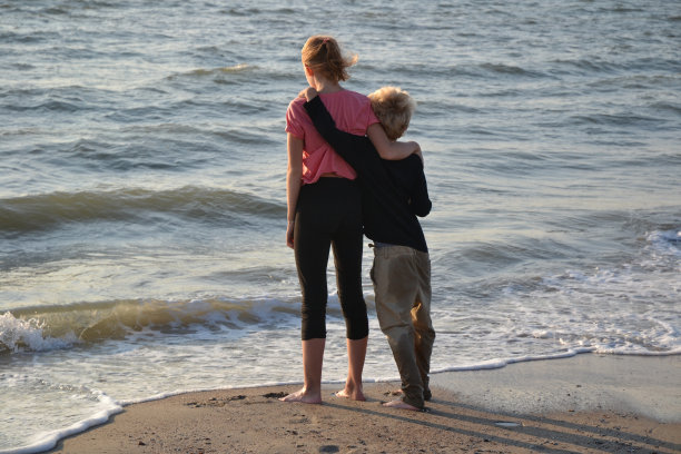 后排的两个孩子在大海面前拥抱在一起图片下载