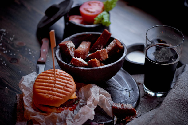 在黑暗的酒吧里的大蒜面包丁汉堡。丰盛的、快速的午餐。大气的照片。黑啤酒图片下载