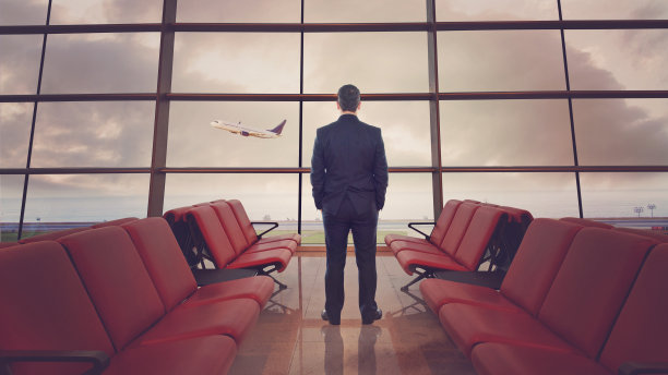 一个商人盯着窗外的机场和一架起飞的飞机图片下载