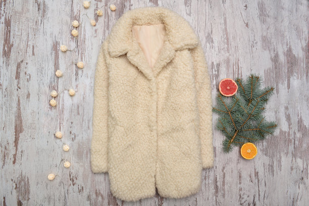 白色的毛皮大衣和在木制背景上的毛皮树枝。时尚的概念图片下载