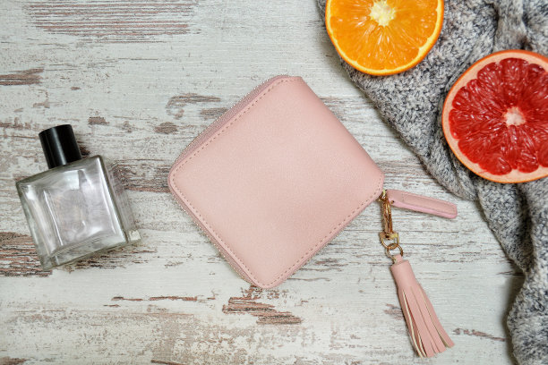 木质背景上的小粉色女性钱包，香水和柑橘。时尚的概念。图片下载