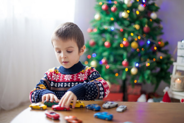 可爱的学前班小男孩，圣诞节在家玩玩具车图片下载