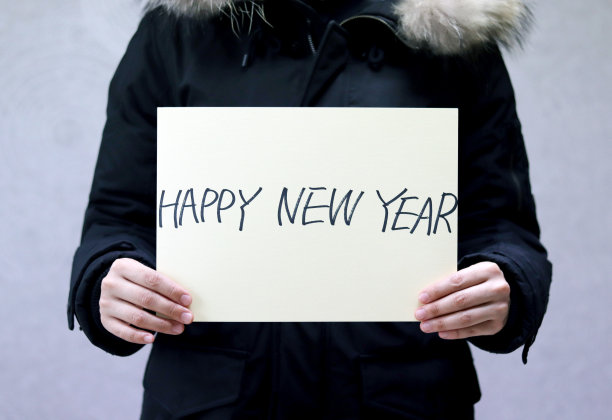 一个女人穿着黑色的毛衣，拿着一张新年贺卡图片下载