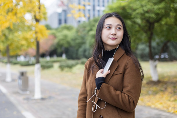 一个年轻女子在秋天的街上听音乐图片下载