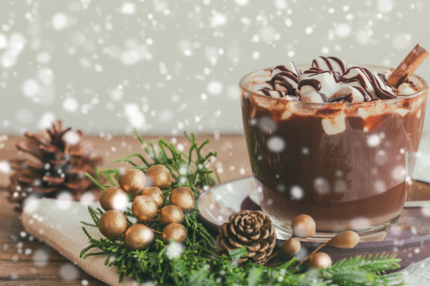 热巧克力在透明的玻璃浇上棉花糖和黑巧克力酱在侧面的木桌上，复制空间与圣诞主题和雪花背景。概念呈现圣诞饮品。图片下载