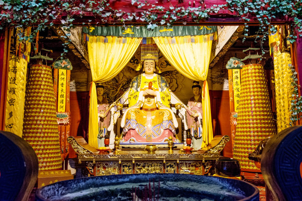 寺庙里有一个坐着的和尚的雕像，一个漂亮的寺庙和一个弯曲的屋顶。中国图片下载