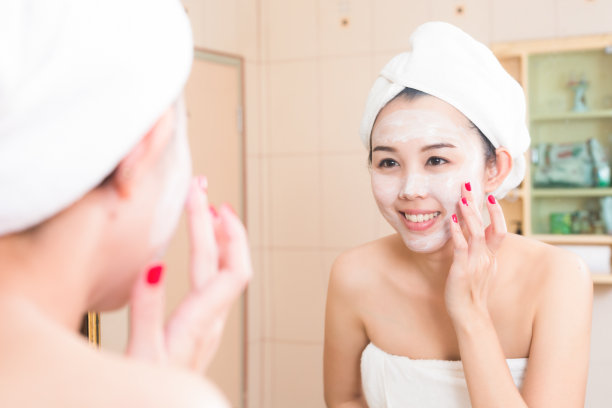 用浴巾涂抹面霜的年轻女子特写图片下载