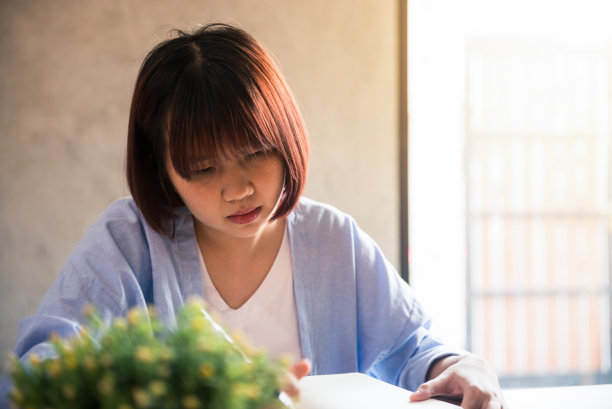 年轻的女商人穿着白色的衣服坐在桌子上写在笔记本上。一个亚洲女人一边喝着咖啡一边聊着手机。在咖啡店工作的自由职业者。复古效果风格图片图片下载