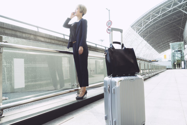 女商人在机场/车站拿着行李箱打电话的肖像图片下载