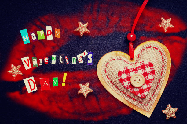 用红色唇膏上刻有字母和心形的纸条做成的“情人节快乐”图片下载