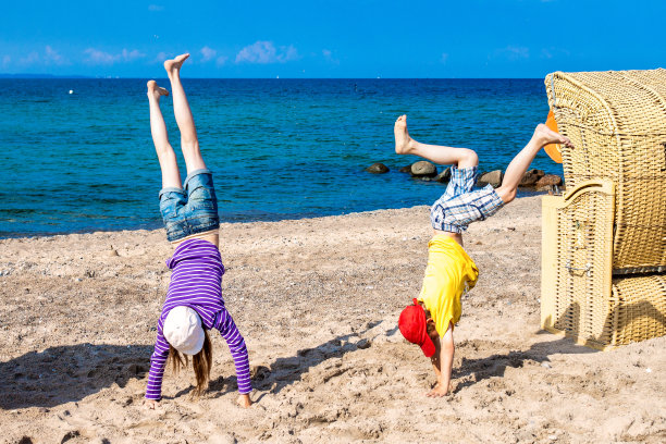 男孩和女孩做倒立轮在海滩上跳动图片下载
