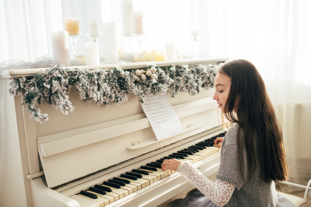 一个可爱的女孩坐在一架白色的钢琴前图片下载