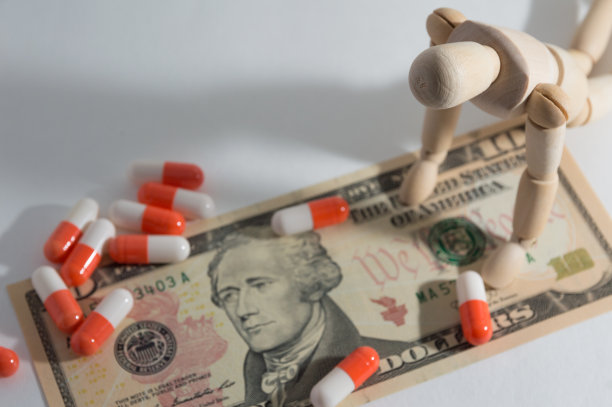 木制的关节娃娃跪在美元和药丸图片下载