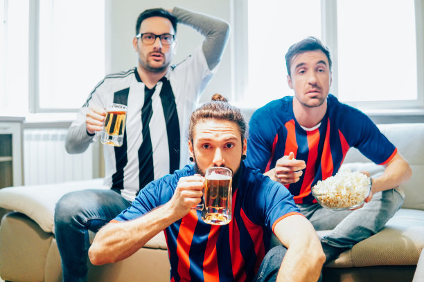 焦虑的朋友看电视上的足球比赛，喝啤酒和吃爆米花图片下载