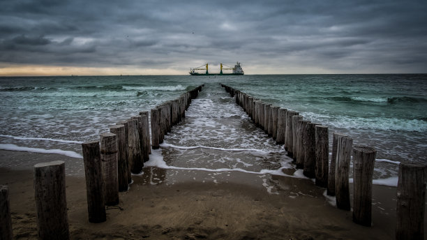 在荷兰泽兰的Vlissingen海滩上，多云的天气里，一艘大船正穿过木制码头图片下载
