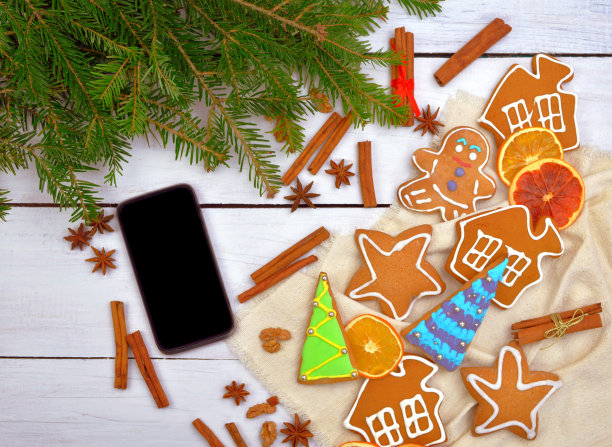 时尚的礼物是一部智能手机。木桌上放着一部电话和一件节日的金属饰品。姜饼。前视图。圣诞节的背景。新年。图片下载