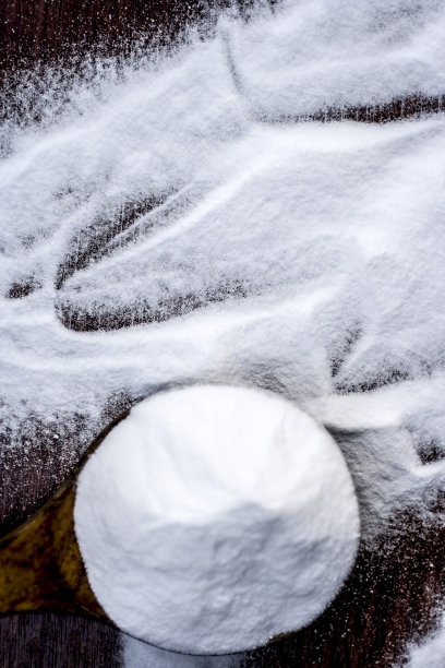 用木勺舀小苏打或碳酸氢钠，放在棕色的木头表面。图片下载